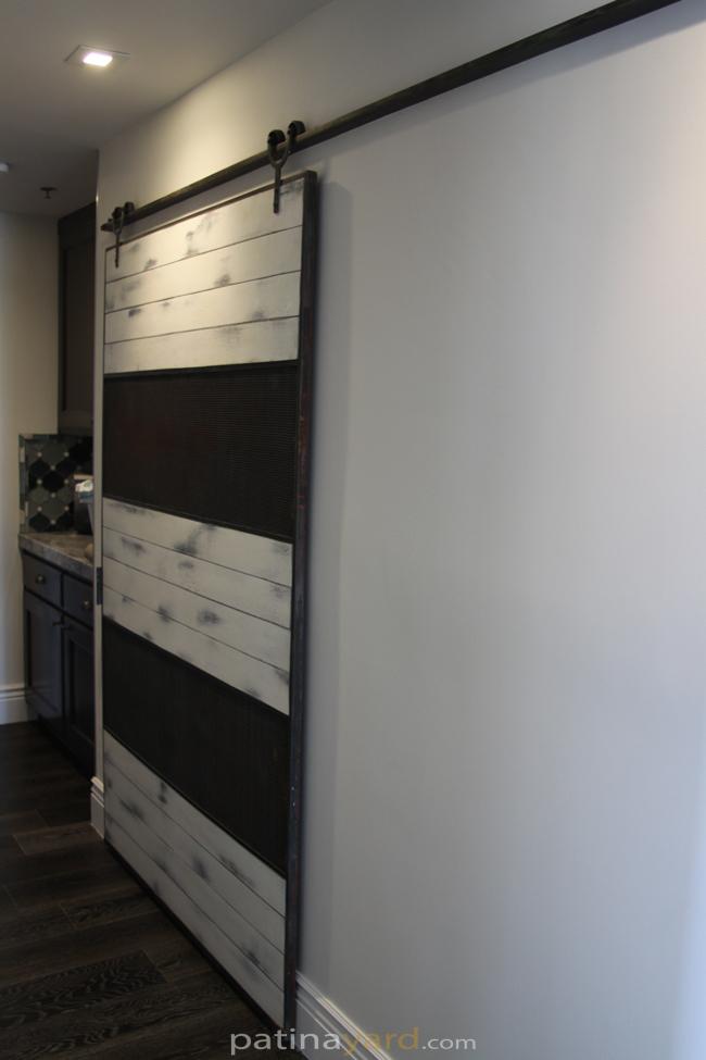 ranch style barn door with wire mesh and white weathered paint