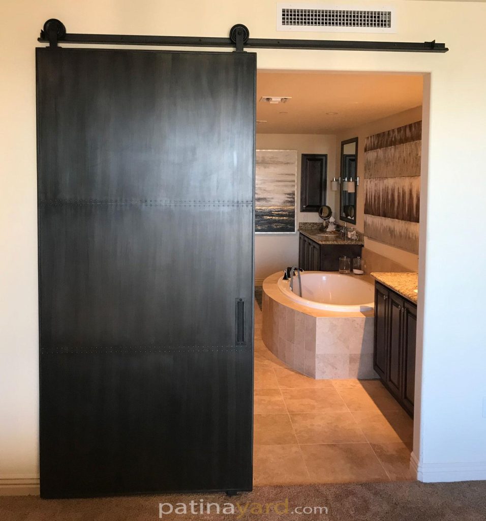metal barn door with a patina finish and custom hardware